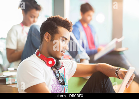 University student using digital tablet in lounge Stock Photo