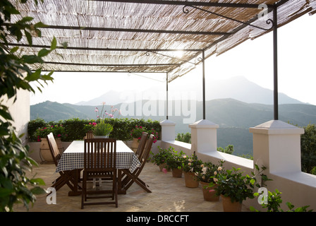Table and chairs on balcony overlooking mountains Stock Photo