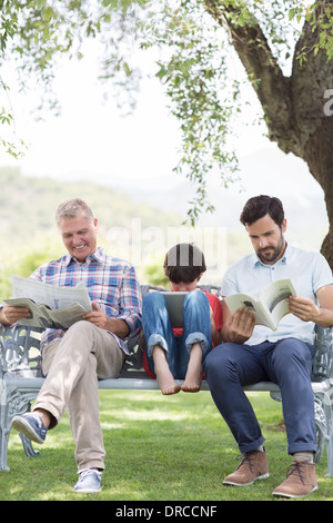 Multi-generation men reading on bench Stock Photo