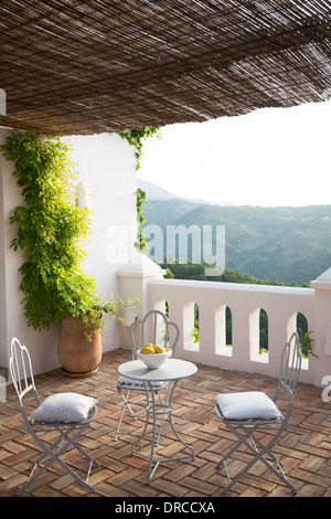Table and chairs on balcony overlooking mountain Stock Photo