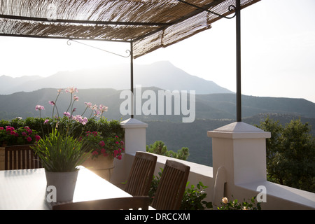 Table and chairs on balcony overlooking mountains Stock Photo