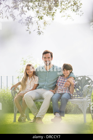 Father and children relaxing on park bench Stock Photo