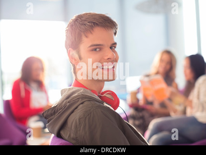 Smiling university student wearing headphones in lounge Stock Photo