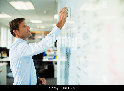 Businessman writing on whiteboard in office Stock Photo