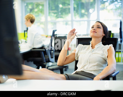 Businesswoman relaxing with feet up on desk in office Stock Photo