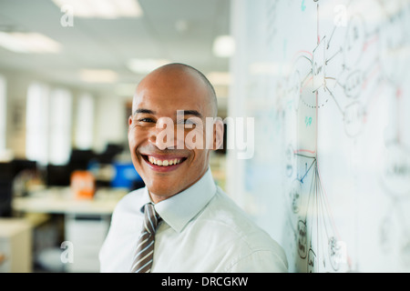 Businessman smiling at whiteboard in office Stock Photo