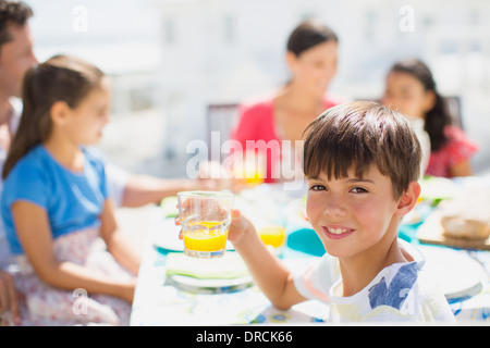 Boy drinking juice at table on sunny patio Stock Photo