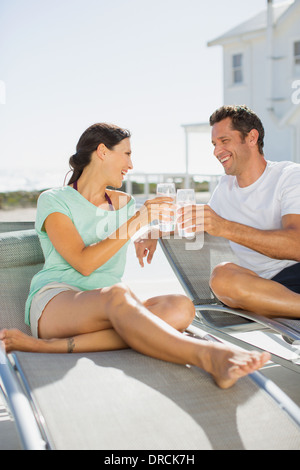 Couple toasting glasses on lounge chairs Stock Photo