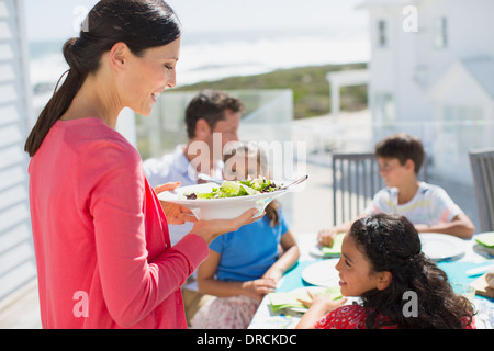 Family eating lunch at table on sunny patio Stock Photo