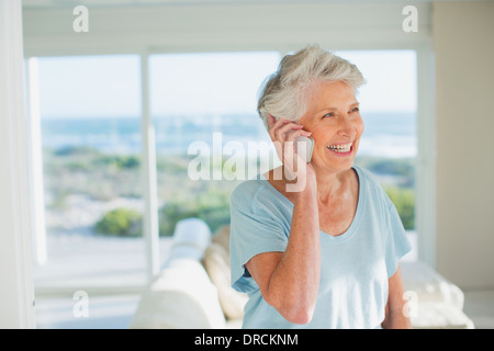 Senior woman talking on cell phone in sunny living room Stock Photo