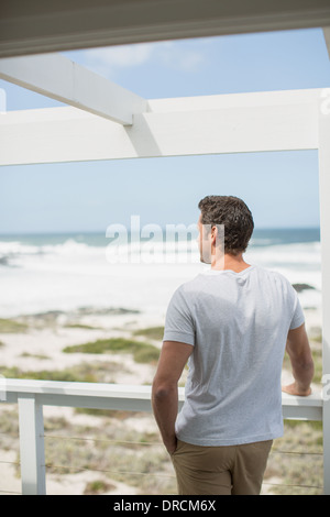 Man looking at ocean view from balcony Stock Photo