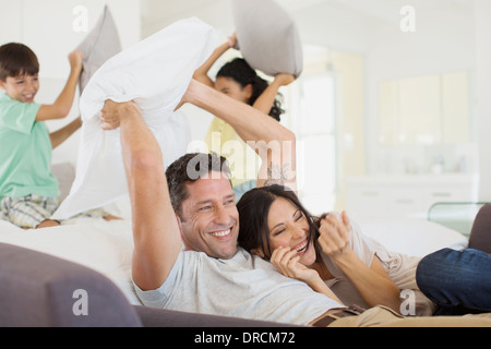 Family enjoying pillow fight in living room Stock Photo