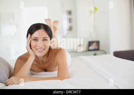 Smiling woman laying on bed Stock Photo