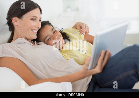 Mother and daughter using digital tablet on sofa Stock Photo