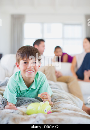 Boy counting change in piggy bank on sofa in living room Stock Photo