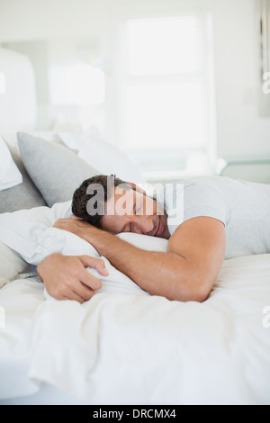 Man hugging pillow on bed Stock Photo
