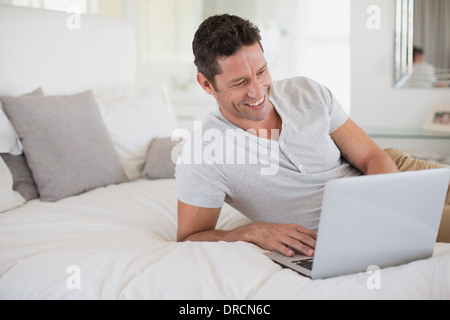 Man using laptop on bed Stock Photo