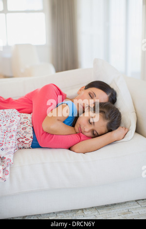 Mother and daughter napping on sofa in living room Stock Photo