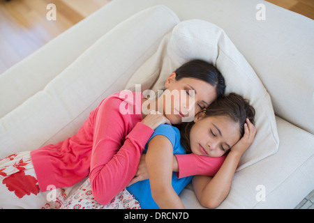 Mother and daughter napping on sofa in living room Stock Photo