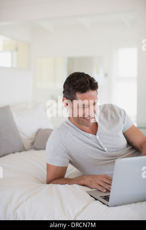 Man using laptop on bed Stock Photo