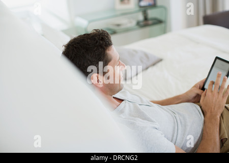 Man using digital tablet on bed Stock Photo