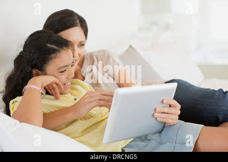 Mother and daughter using digital tablet on bed Stock Photo