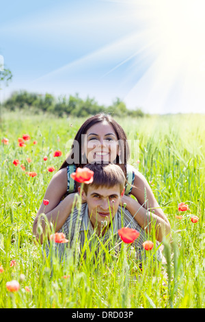 Couple in poppy field, lying down, close up faces Stock Photo