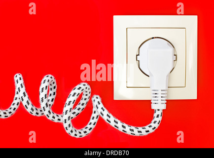 Textile power cord and power socket against a red background Stock Photo