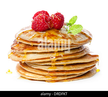 Small pancakes topped with honey, raspberries and mint on white background Stock Photo