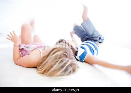 Brother and sister rolling on bed Stock Photo