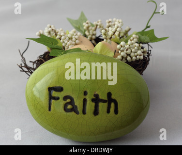 Green Rock with the word Faith on it in front of a nest with eggs in it. Stock Photo