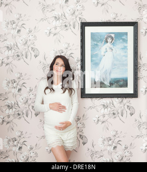 Pregnant woman in front of floral wall Stock Photo