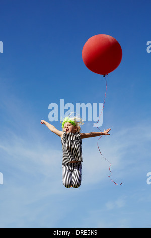 girl jumping in the air with a red balloon Stock Photo