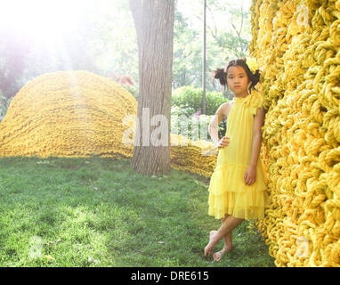 Young asian girl in yellow dress near yellow wall Stock Photo