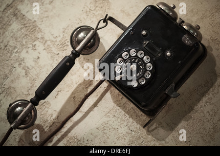 Vintage black phone hanging on old gray concrete wall Stock Photo
