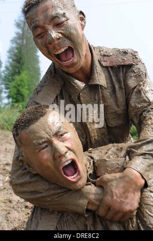 MUDDY COPS These are no bog-standard training methods. Rookie police wannabes are literally dragged into the mire by their tough, non nonsense boot camp drill sergeant as they slog through the swampy terrain. Each participant at the Police Training College in Chuzhou City, Anhui Province, China, aims to graduate from aspiring boys-in-blue aim to graduate to full-fledged copper . .  Stock Photo