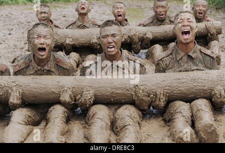 MUDDY COPS These are no bog-standard training methods. Rookie police wannabes are literally dragged into the mire by their tough, non nonsense boot camp drill sergeant as they slog through the swampy terrain. Each participant at the Police Training College in Chuzhou City, Anhui Province, China, aims to graduate from aspiring boys-in-blue aim to graduate to full-fledged copper . .  Stock Photo