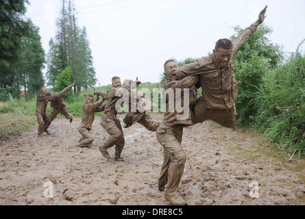 MUDDY COPS These are no bog-standard training methods. Rookie police wannabes are literally dragged into the mire by their tough, non nonsense boot camp drill sergeant as they slog through the swampy terrain. Each participant at the Police Training College in Chuzhou City, Anhui Province, China, aims to graduate from aspiring boys-in-blue aim to graduate to full-fledged copper . .  Stock Photo