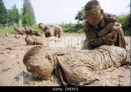 MUDDY COPS These are no bog-standard training methods. Rookie police wannabes are literally dragged into the mire by their tough, non nonsense boot camp drill sergeant as they slog through the swampy terrain. Each participant at the Police Training College in Chuzhou City, Anhui Province, China, aims to graduate from aspiring boys-in-blue aim to graduate to full-fledged copper . .  Stock Photo