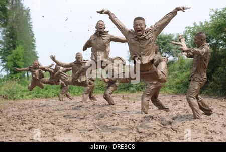 MUDDY COPS These are no bog-standard training methods. Rookie police wannabes are literally dragged into the mire by their tough, non nonsense boot camp drill sergeant as they slog through the swampy terrain. Each participant at the Police Training College in Chuzhou City, Anhui Province, China, aims to graduate from aspiring boys-in-blue aim to graduate to full-fledged copper . .  Stock Photo