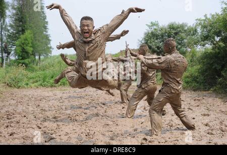 MUDDY COPS These are no bog-standard training methods. Rookie police wannabes are literally dragged into the mire by their tough, non nonsense boot camp drill sergeant as they slog through the swampy terrain. Each participant at the Police Training College in Chuzhou City, Anhui Province, China, aims to graduate from aspiring boys-in-blue aim to graduate to full-fledged copper . .  Stock Photo