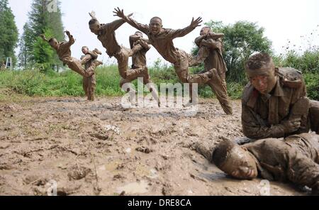 MUDDY COPS These are no bog-standard training methods. Rookie police wannabes are literally dragged into the mire by their tough, non nonsense boot camp drill sergeant as they slog through the swampy terrain. Each participant at the Police Training College in Chuzhou City, Anhui Province, China, aims to graduate from aspiring boys-in-blue aim to graduate to full-fledged copper . .  Stock Photo