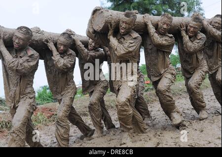 MUDDY COPS These are no bog-standard training methods. Rookie police wannabes are literally dragged into the mire by their tough, non nonsense boot camp drill sergeant as they slog through the swampy terrain. Each participant at the Police Training College in Chuzhou City, Anhui Province, China, aims to graduate from aspiring boys-in-blue aim to graduate to full-fledged copper . .  Stock Photo