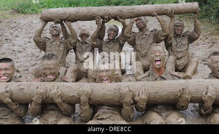 MUDDY COPS These are no bog-standard training methods. Rookie police wannabes are literally dragged into the mire by their tough, non nonsense boot camp drill sergeant as they slog through the swampy terrain. Each participant at the Police Training College in Chuzhou City, Anhui Province, China, aims to graduate from aspiring boys-in-blue aim to graduate to full-fledged copper . .  Stock Photo