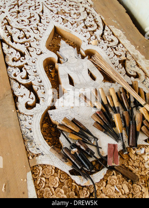 skillful engravements. carving tools are lying on the panel. hand made for a temple in Thailand. Stock Photo
