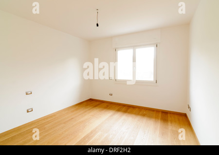 Spacious empty room with white walls, window and parquet floor Stock Photo