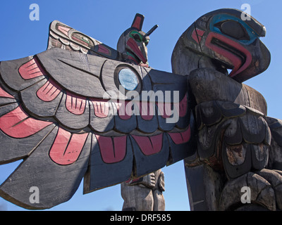 First Nations story pole carvings on show in the street of Duncan, B.C. show an eagle with a raven beyond, against a bright blue Stock Photo