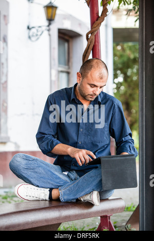 Man Using Tablet PC On Bench, Osijek, Croatia Stock Photo