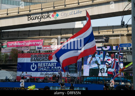 Bangkok, Thailand. Jan. 24th, 2014. An anti-government protester waves the Thai National flag in front of the main stage by MBK shopping mall at the Pratunam intersection. On day 12 of 'Shutdown Bangkok', there are still Tens of thousands of protesters on the streets of Bangkok demanding the resignation of Thai Prime Minister Yingluck Shinawatra. 'Shutdown Bangkok' is organized by the People's Democratic Reform Committee (PDRC). Credit:  Kraig Lieb / Alamy Live News Stock Photo