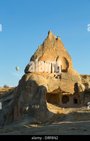Dwelling in fairy chimney and hot air balloon, Swords Valley (Meskendir), near Goreme, Cappadocia, Turkey Stock Photo